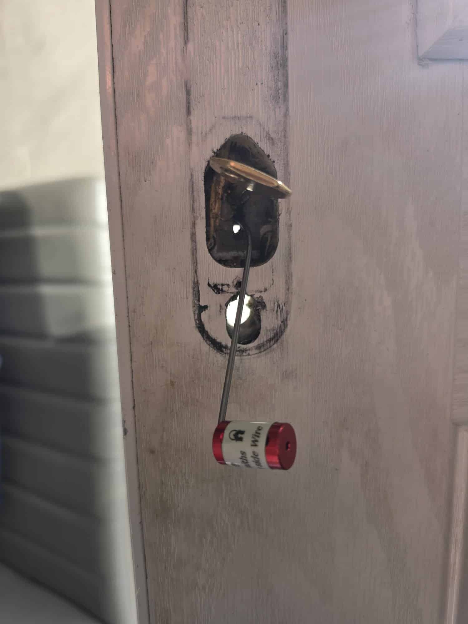 Exposed door lock mechanism with a locksmith tool in place during the Wombourne repair